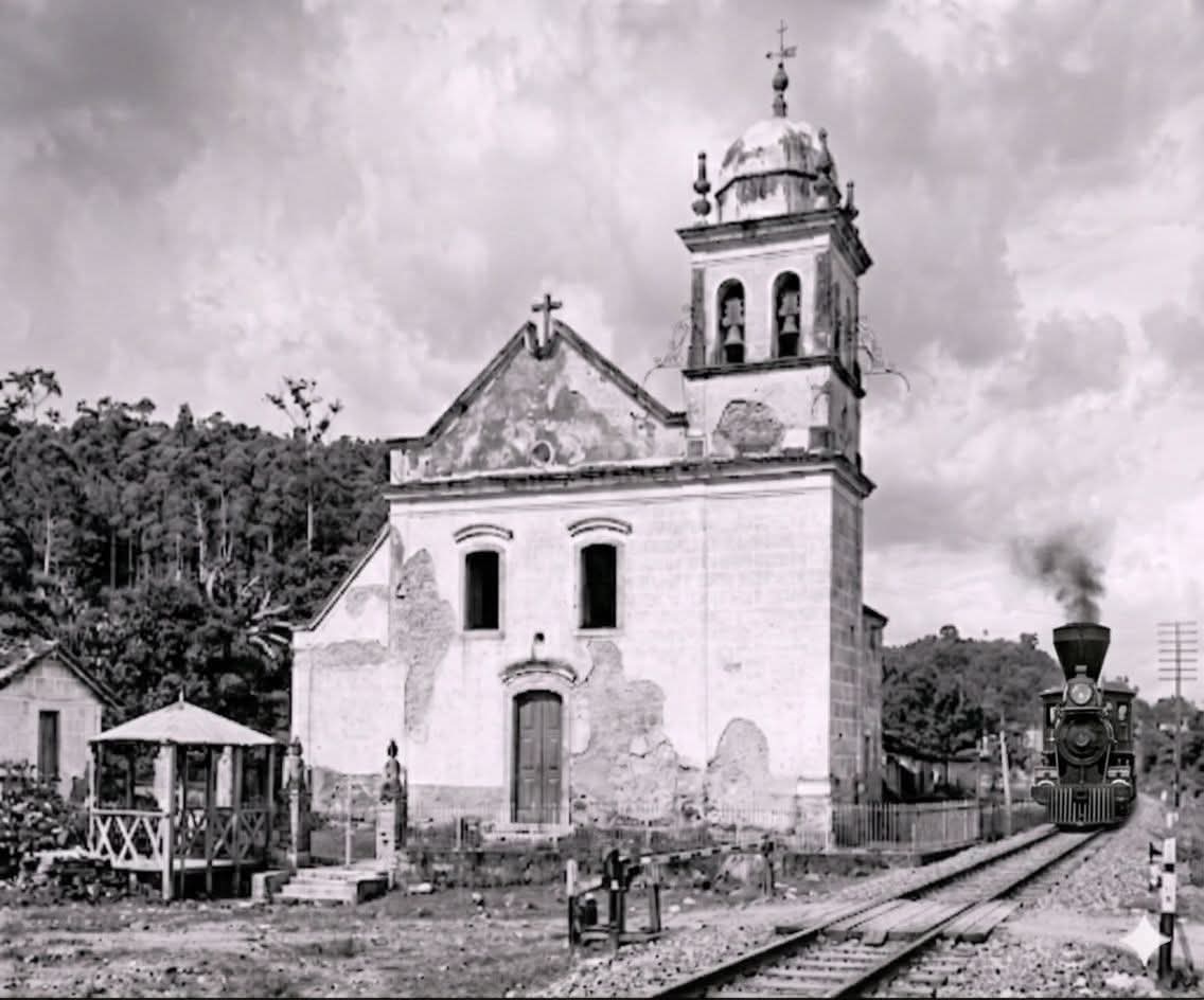 O trem passando ao lado da Igreja de Nossa Senhora do Pilar, Merity atual Duque de Caxias-Rio de Janeiro, em 1907. Onde existia a linha férrea é atualmente Avenida Governador Leonel Brizola (antiga Avenida Presidente Kennedy).